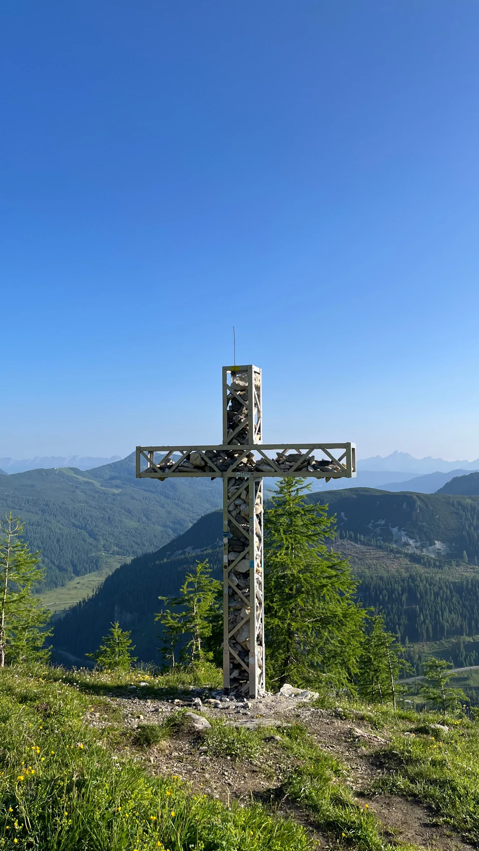Gipfelkreuz vor einer Berglandschaft unter blauem Himmel – ein persönliches Wanderfoto